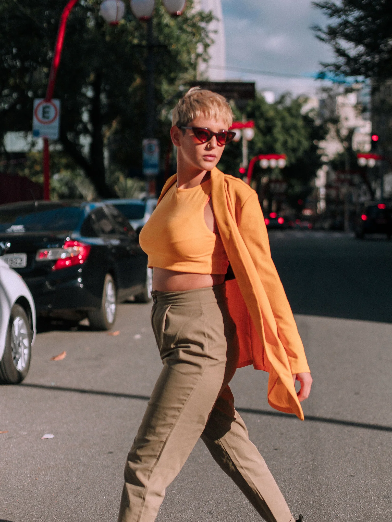 Streetwear fashion editorial of two models in a busy city crosswalk with muted cinematic tones and shallow depth of field.